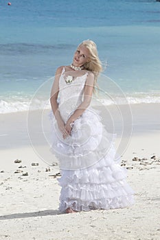 Young beautiful woman in a bride dress standing at sea edge