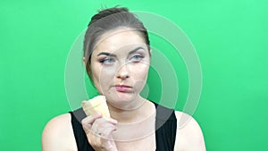 Young beautiful woman with bright evening makeup smoky eyes eating ice cream on a green background