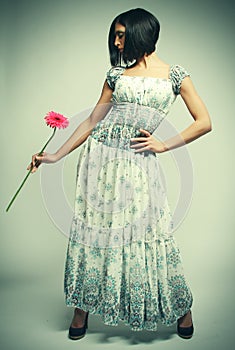 Beautiful woman with bright make up holding pink gerber flower