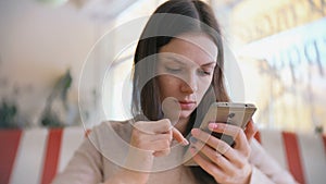 Young beautiful woman brunette typing and sending message in her mobile phone in cafe and waiting her friends.