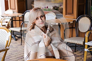 Young beautiful woman, in cafe, drinking coffee in cup, in cozy plaid happy