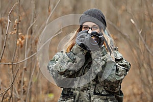 Young beautiful woman in camouflage outfit discovering nature in the forest with photo camera. Travel photography lifestyle