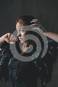 Young beautiful woman in a cape of black feathers in ethnic or tribal style.