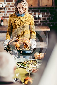 young beautiful woman carrying tray with roasted turkey