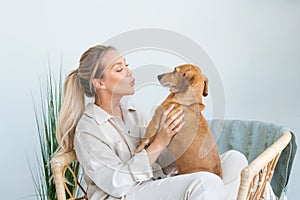 A young beautiful woman in casual clothes hugs and pets her beloved dog sitting