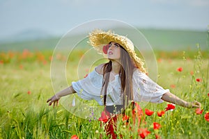 Young beautiful woman on cereal field with poppies in summer