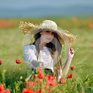 Young beautiful woman on cereal field with poppies in summer