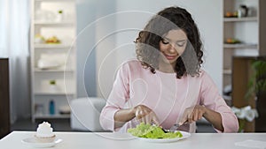 Young beautiful woman choosing salad over cake and eating, healthy food