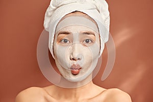 Young beautiful woman with clay face mask. Spa treatment, self care and healthy skin