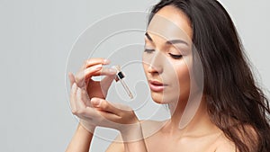 Young beautiful woman with clean perfect skin uses age-sensitive serum in pipette