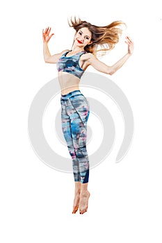 Young beautiful woman in color-blue top and leggings jumping of joy. Young sporty fit emale model isolated on white background in