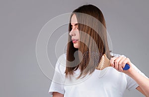 Young beautiful woman combing brown hair. Hair Care. Beautiful brunette woman hairbrushing hair with hairbrush. Brushing