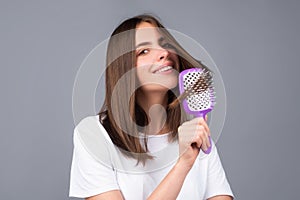 Young beautiful woman combing hair. Hair Care. Beautiful brunette woman hairbrushing hair with hairbrush. Brushing