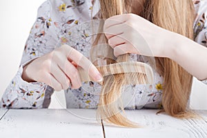 Young beautiful woman combing her hair in living room