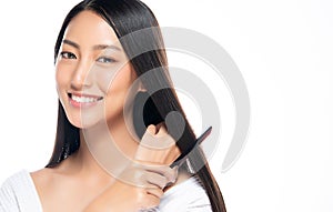 Young beautiful woman combing her hair on white background