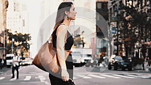 Young beautiful woman crossing the road in traffic downtown of New York, America. Female walking through the crosswalk.