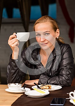 Young beautiful woman with a cup of coffee in a outdoor cafe, girl have a lunch on terrace