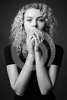Young beautiful woman with curly blond hair against gray background
