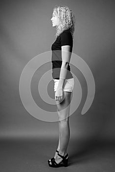 Young beautiful woman with curly blond hair against gray background