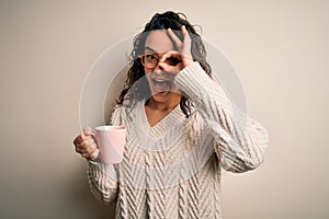 Young beautiful woman with curly hair drinking pink mug of coffee over white background with happy face smiling doing ok sign with