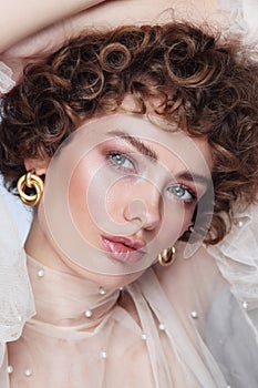 Young beautiful woman with curly hair and glowing partyl makeup