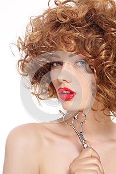 Beautiful woman with curly hair and hairdressing scissors in her hand