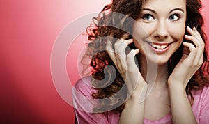 Young beautiful woman with curly hair over pink background