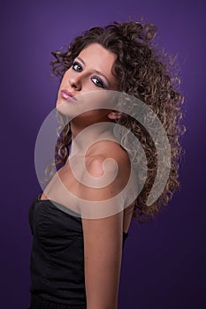 Young, beautiful woman with curly hair on purple