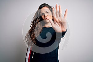 Young beautiful woman with curly hair wearing casual sweater over isolated white background doing stop sing with palm of the hand photo