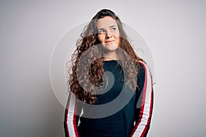 Young beautiful woman with curly hair wearing casual sweater over isolated white background smiling looking to the side and