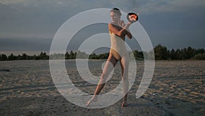 Young beautiful woman is dancing with fire wearing body suit on sunrise in the desert