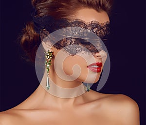 Young beautiful woman with dark lace on eyes bare shoulders and neck, jewelry earrings, feeling temptation, passion sex red l