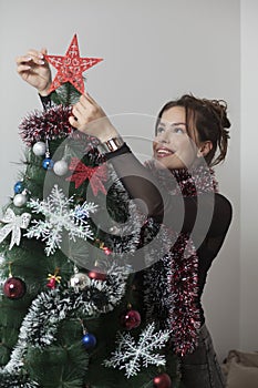 Young beautiful woman decorating Christmas tree