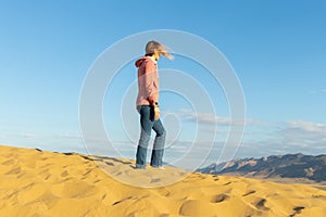 Young beautiful woman among the desert Barkhan Sarykum in autumn time.Republic of Dagestan,october 2022.