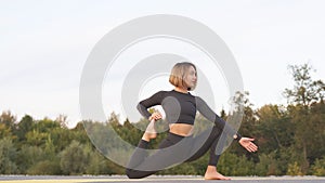 Young beautiful woman doing core workout on road outdoors near the forest