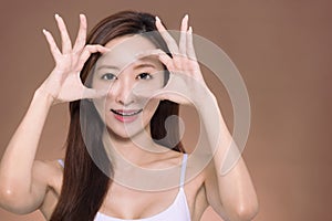 Young beautiful  woman  doing ok gesture with hand smiling, eye looking through fingers with happy face