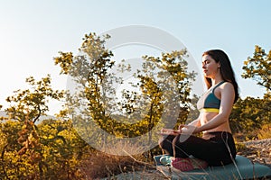 Young beautiful woman doing yoga and meditating in the Park. The concept of yoga, sports and meditation. Copy space