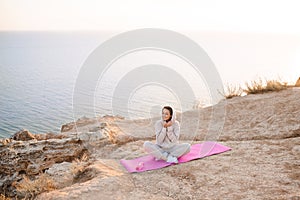 Young beautiful woman doing yoga pose wear sport suit practice over nature sea background. Healthy lifestyle.