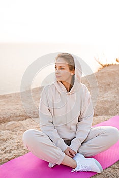 Young beautiful woman doing yoga pose wear sport suit practice over nature sea background. Healthy lifestyle.