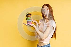 Young beautiful woman with doughnuts on yellow background