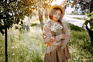 Young Beautiful Woman Holding Bunch Of Dandelion Flowers Standing On Meadow