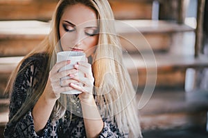 Young beautiful woman drinking cocoa in a wooden coutry house