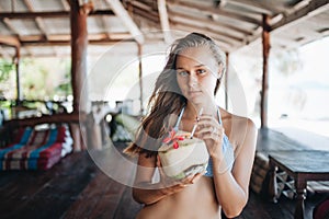 Young beautiful woman drinking coconut water in thai cafe photo