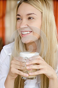 A young beautiful woman is drinking from a cup