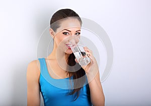 Young beautiful woman drinking fresh pure water from glass on bl