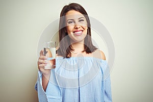 Young beautiful woman drinking a glass of fresh water over isolated background with a happy face standing and smiling with a