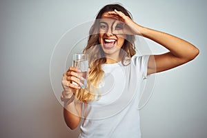 Young beautiful woman drinking a glass of water over white isolated background with happy face smiling doing ok sign with hand on