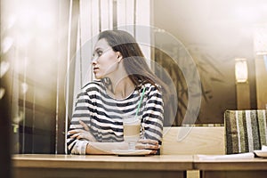 Young beautiful woman drinking latte in the coffee shop at a tab