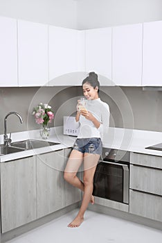 Young beautiful woman drinking milk in the kitchen morning