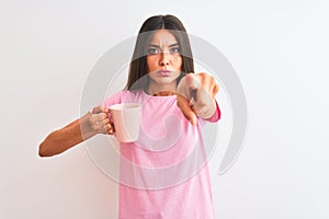 Young beautiful woman drinking pink cup of coffee standing over isolated white background pointing with finger to the camera and